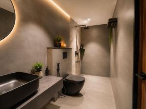 a bathroom with a black toilet and a sink at Hotel Vdara Bliss in Vijayawāda