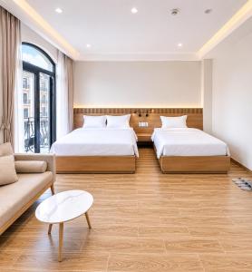 a hotel room with two beds and a couch at K-Dragon Hotel Đồi Rồng, Đồ Sơn in Ðông Thôn +21 photos