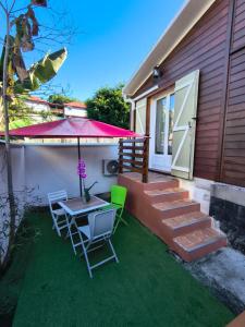 a patio with a table and chairs and an umbrella at Chez Frida in Entre-Deux