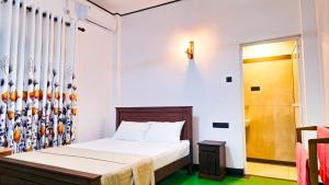 a small bedroom with a bed and a door at Surf and stay in Weligama