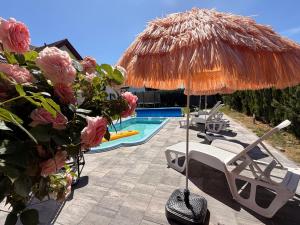 a patio with a straw umbrella and chairs and a swimming pool at Złote Piaski Pensjonat z basenem in Darłowo