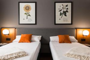 two beds in a room with pictures on the wall at Hotel Malcom and Barret in Valencia +102 photos
