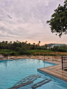 a swimming pool with a wooden walkway and trees at Hotel Elephant Bay - World's Best Place to See the Elephants in Pinnawala
