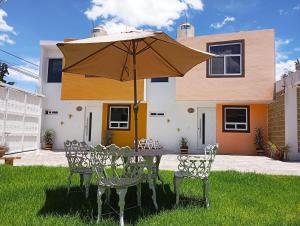 a table with an umbrella in front of a house at Loft los Colibries 6 parking option in Tlaxcala de Xicohténcatl