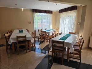 a dining room with two tables and wooden chairs at Silentium Clavem Domus III. in Odorheiu Secuiesc