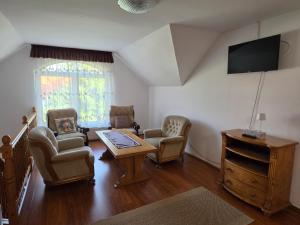 a living room with chairs and a table and a tv at Silentium Clavem Domus III. in Odorheiu Secuiesc