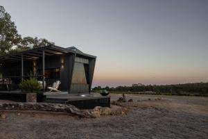 a small black house on a field with the sunset at Heyscape Busselton in Busselton +22 photos
