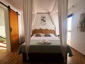 a bedroom with a canopy bed with two towels on it at B&B SEnDA de alegria in Cómpeta