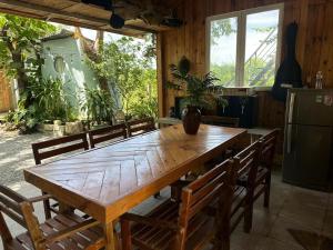 a wooden table in a room with chairs and a refrigerator at Homestay Vườn Của Gió in Ấp Thanh Sơn (1)