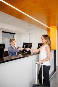 two women standing at a counter with a suitcase at Quest Port Adelaide in Adelaide