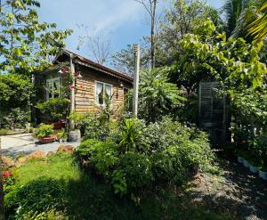 a small wooden house with plants in front of it at Homestay Vườn Của Gió in Ấp Thanh Sơn (1)