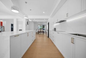a white kitchen with white cabinets and a wooden floor at Stunning Waterfront Escape in Gold Coast