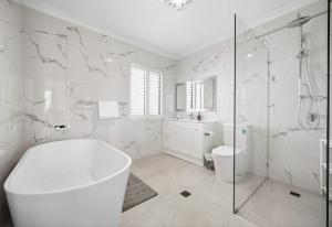a white bathroom with a tub and a toilet at Stunning Waterfront Escape in Gold Coast +7 photos