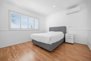 a white bedroom with a bed and a window at Stunning Waterfront Escape in Gold Coast