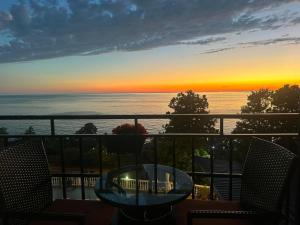 a sunset from a balcony with a table and chairs at White House Chakvi in Chakvi