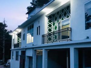 a white building with a balcony and a window at EmberGuestHouse in Abbottabad
