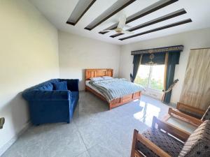 a bedroom with a bed and a blue couch at EmberGuestHouse in Abbottabad +3 photos