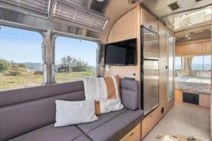 an interior of an rv with a couch and a television at Yosemite's Best Glamping Airstream Experience! in Coarsegold