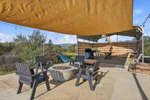 a patio with three chairs and a fire pit at Yosemite's Best Glamping Airstream Experience! in Coarsegold