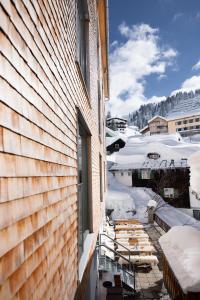 a building with snow on the ground next to a window at Ski Hotel Mondschein 1739 in Stuben am Arlberg