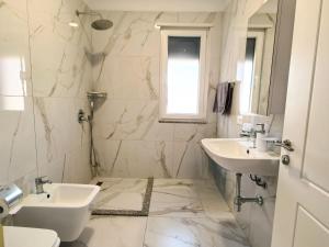 a white bathroom with two sinks and a mirror at Enjoy Shkodra Apartment in Shkodër +21 photos