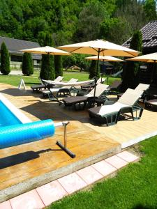 a swimming pool with lounge chairs and umbrellas and a pool at Alpenhaus in Voineasa
