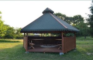 a gazebo with a fire pit in the grass at Domki U Grega na kaszubach in Wiele