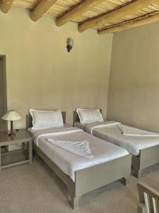 two twin beds in a room with a table at Lharje Resort in Satti