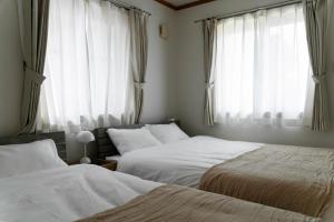 a bedroom with two beds and a window at Nagano Villa 翠 in Nagano