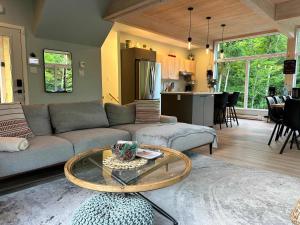 a living room with a couch and a table at Le RuissO - Spa et Confort in Brownsburg