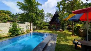 a swimming pool in a yard with an umbrella at Green Breeze Villa in Katugastota