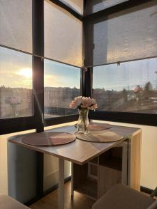 a table with a vase of flowers in a room with windows at MOuntain View Apartment in Câmpulung