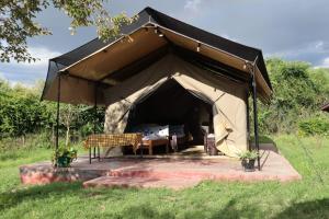 a large tent with a bench in a field at Sunshine maasai mara safari camp in Sekenani