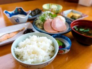 a wooden table with bowls of rice and other foods at Eshin no Sato Yasuragisou in Joetsu +5 photos