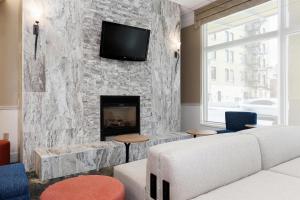 a living room with a fireplace with a tv on a stone wall at Hilton Garden Inn Ithaca in Ithaca