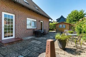 a patio of a brick house with a table and chairs at Haus Achtern Diek - Ferienwohnungen in Wangerland