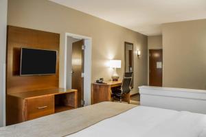 a hotel room with a bed and a desk with a television at Comfort Suites Hartville-North Canton in Uniontown +63 photos