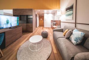 a living room with a couch and a tv at Das Sonnreich - Thermenhotel Loipersdorf in Loipersdorf bei Fürstenfeld