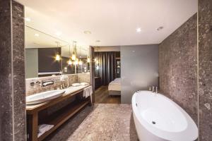 a bathroom with a tub and a large mirror at Das Sonnreich - Thermenhotel Loipersdorf in Loipersdorf bei Fürstenfeld +82 photos
