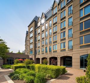 a large building with bushes in front of it at DoubleTree by Hilton North Vancouver in North Vancouver