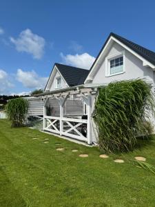 a white house with a white fence and grass at MarinaMar Karwia in Sławoszynko