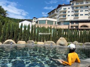 a woman sitting in a pool in front of a building at STX Resort in Mungyeong