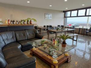 a living room with couches and a table and tables at HOTEL&RESORT Izu no Ne in Higashiizu