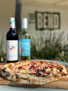a pizza on a cutting board with two bottles of wine at Ingenia Holidays Murray Bend in Koonoomoo +48 photos