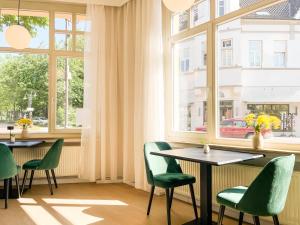 a restaurant with green chairs and tables and windows at Hotel Salina B&B - mit Parkplatz, Zentral und Digital in Bad Rothenfelde