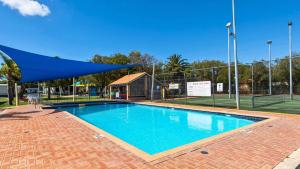a swimming pool with a tennis court in the background at The Beach Quarters in Broadwater