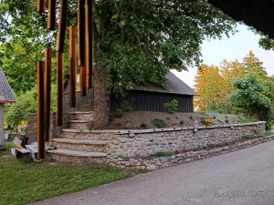 a house with a stone wall and some stairs at Gaismas klēts in Upmaļciems +31 photos
