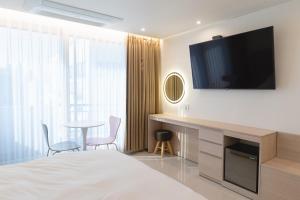 ein Hotelzimmer mit Bett, Fernseher und Tisch in der Unterkunft MH Hotel 2 in Jeonju