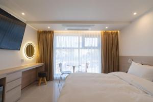 ein Schlafzimmer mit einem Bett, einem Tisch und einem Fenster in der Unterkunft MH Hotel 2 in Jeonju