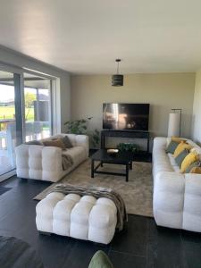 a living room with two white couches and a tv at Villa Houtave in Zuienkerke